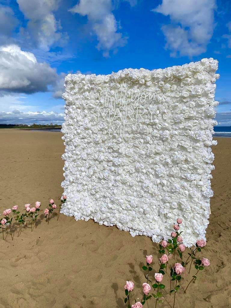 Proposal flower wall on the beach. White flowers. Bespoke proposals beach set up. Flower wall